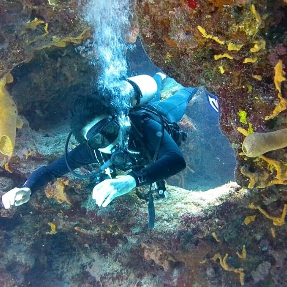 A scuba diver swimming through th reef at Devils Throat